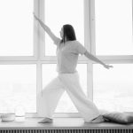 Woman practicing yoga indoors, in a stylish black and white ambiance.