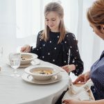 A serene scene of a mother and daughter dining together in a bright, cozy setting.